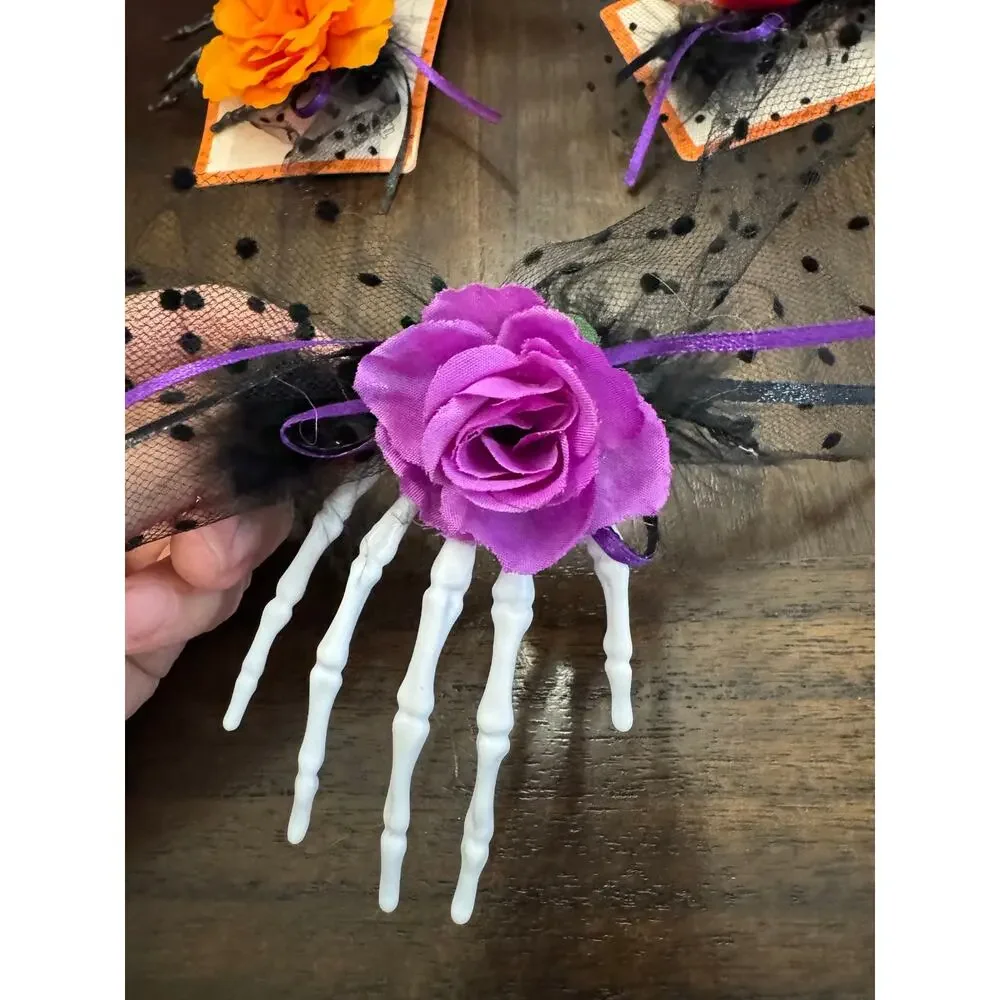 Purple rose hair clip with black netting and purple ribbon on a skeleton hand